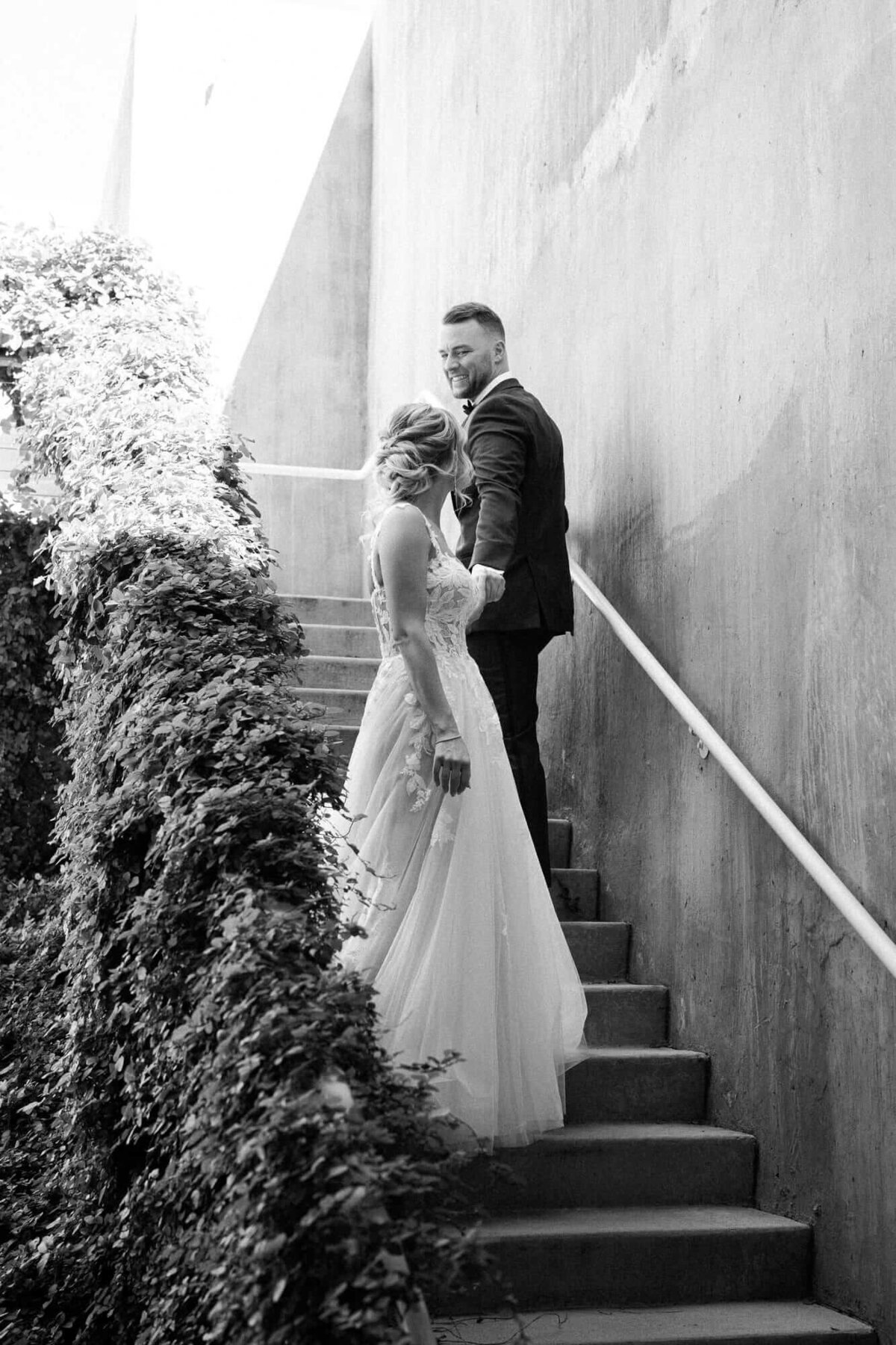 Black and white photo of a bride and groom holding hands on the staircase at Mountain Shadows in Scottsdale, Arizona.