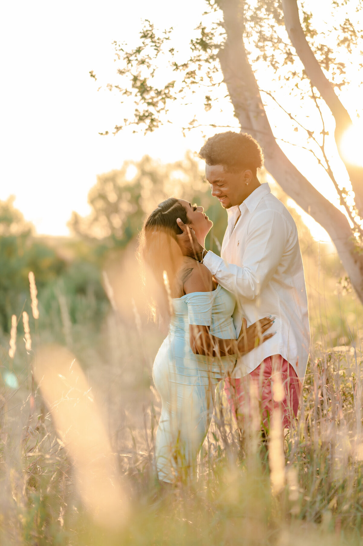 Pregnant couple embraces during sunrise glow. Professional maternity photography at Phil Hardberger Park in San Antonio.