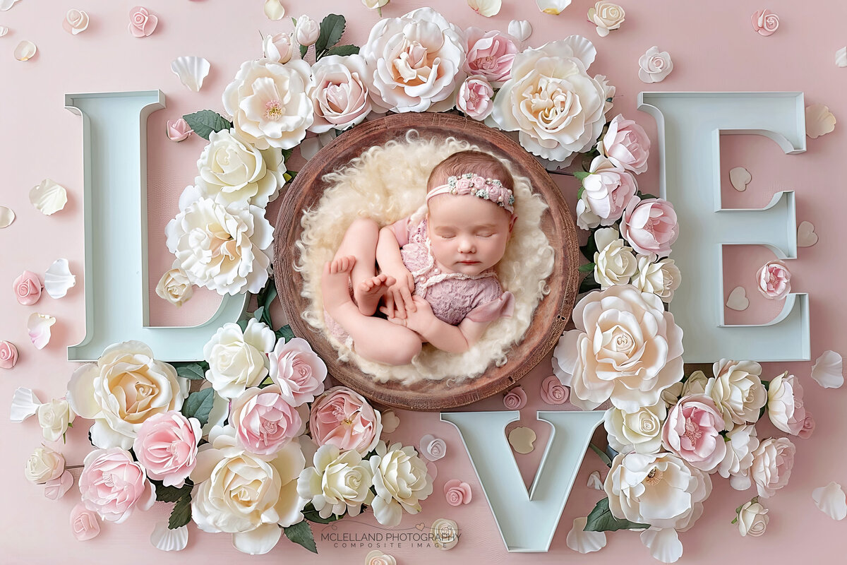 Newborn girl posed in bright floral LOVE letters with soft pastel theme