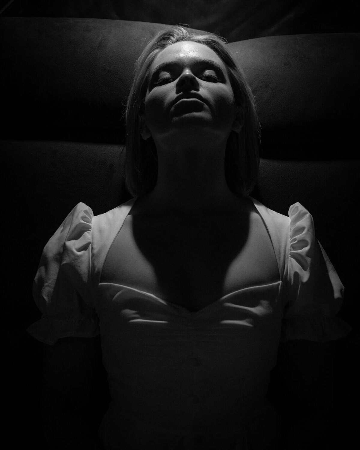 A bride closes her eyes and leans into the downlight which brightens her face