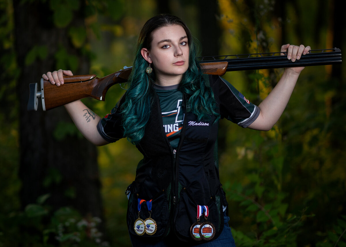 An image from the studio of a Pella Senior Photographer of a shooting champion showing off her medals in her team jersey