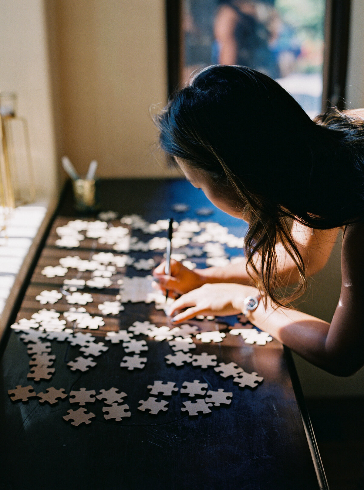 Wedding guest writing a message on puzzle pieces for a creative guest book alternative at Castle Ladyhawke. 