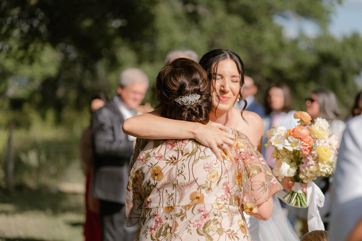 at the end of the isle the bride hugs her mom