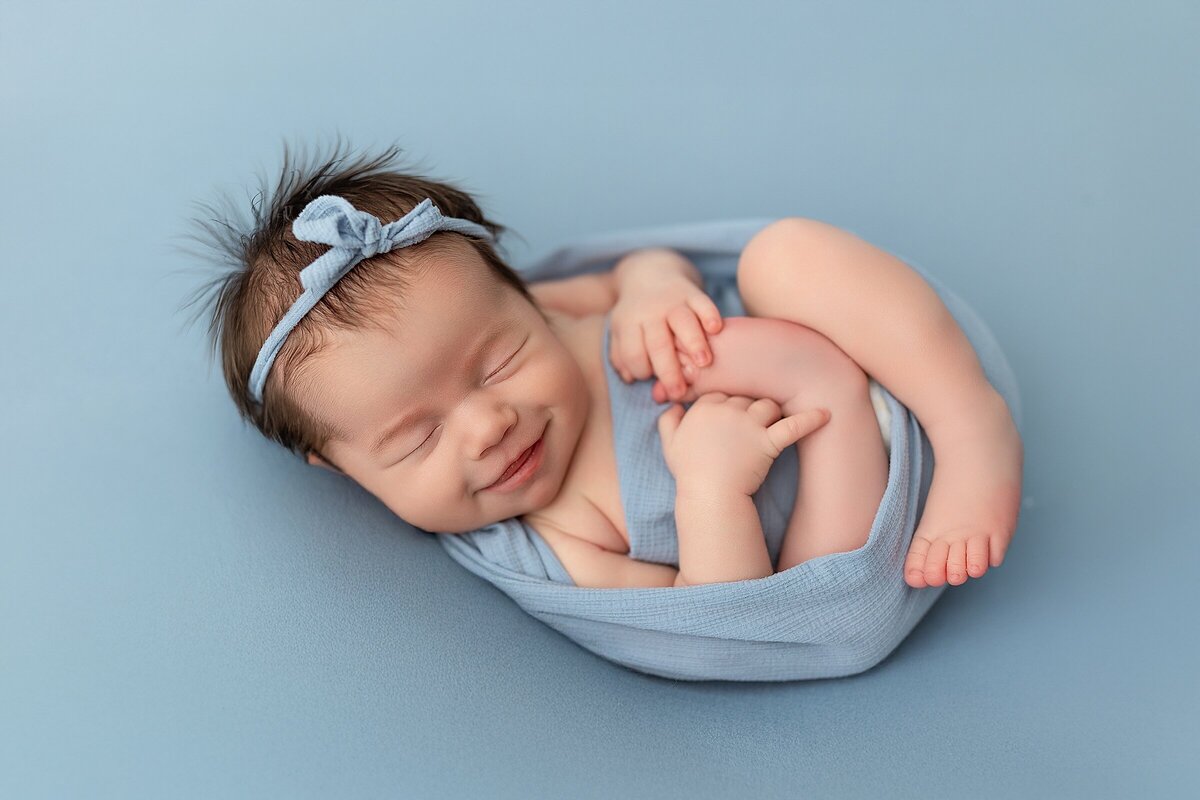 posed newborn photography baby girl in blue smiling