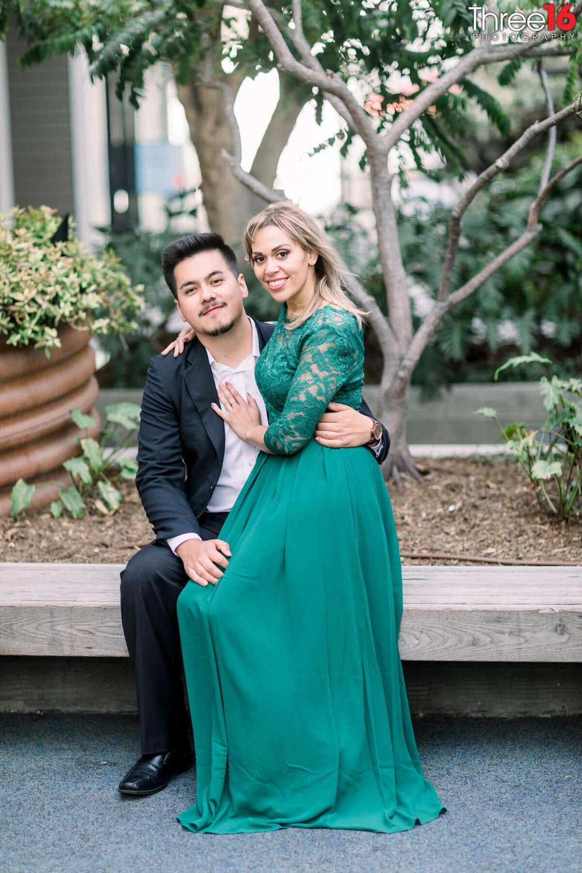 Bride to be sits on her Groom's lap during photo session