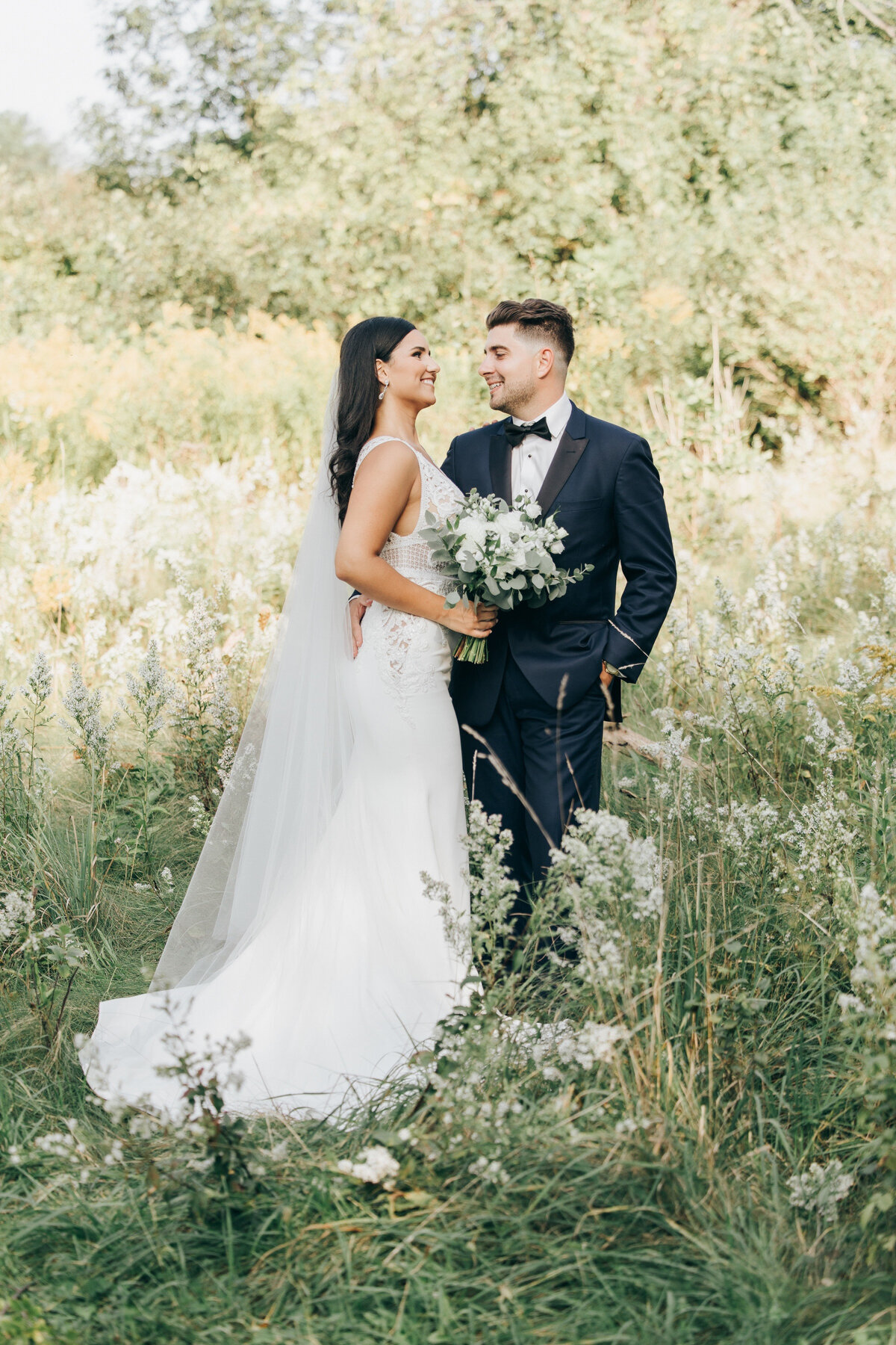 A bride and groom posing in a field