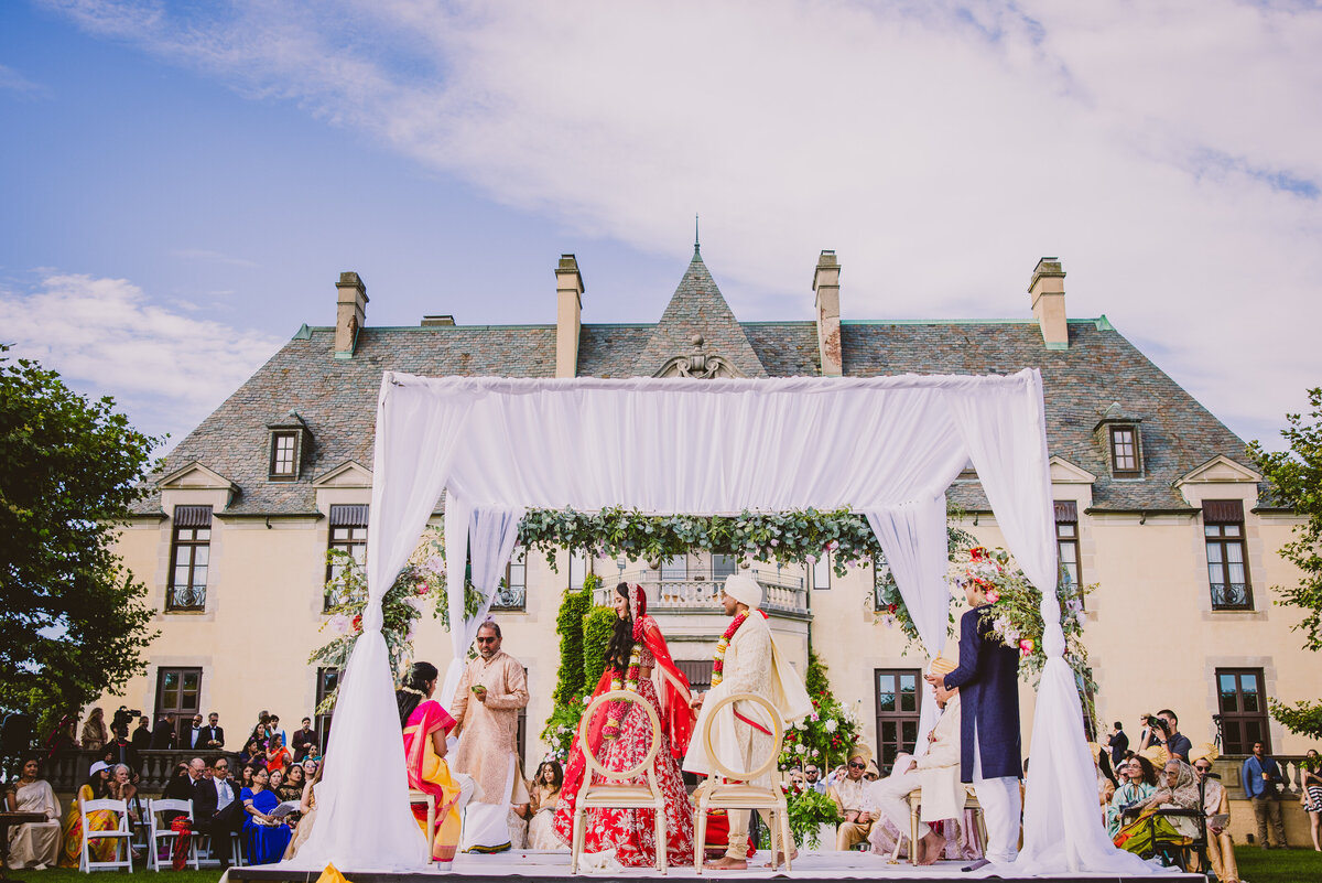 south asian indian hindu bride and groom walking around the fire during the wedding ceremony under the mandap at oheka castle
