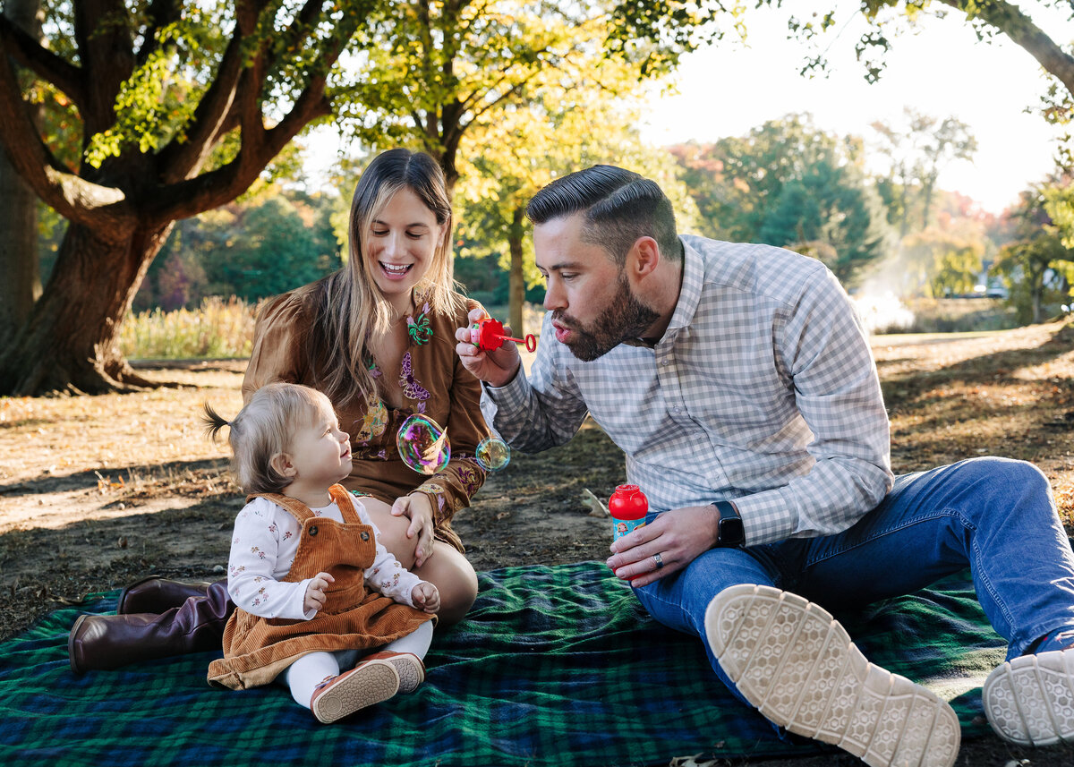 Lifestyle photo of family smiling and blowing bubbles at a Union County, NJ park in the fall.
