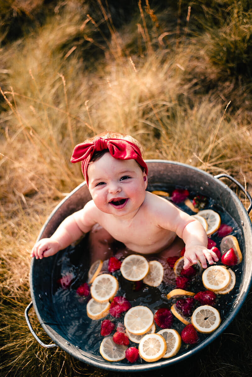 Happy baby girl in fruit bath during family photography session