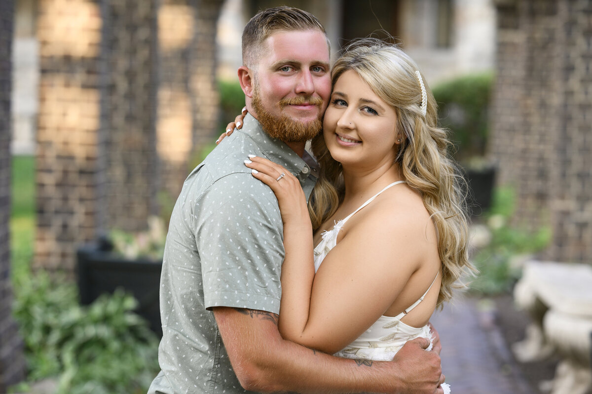 A couple smiling and embracing in a romantic outdoor setting