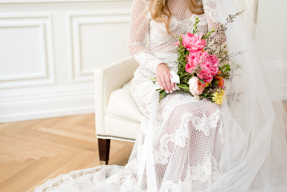 Bride sitting down holding a colorful vibrant bouquet in Fort Worth wedding venue