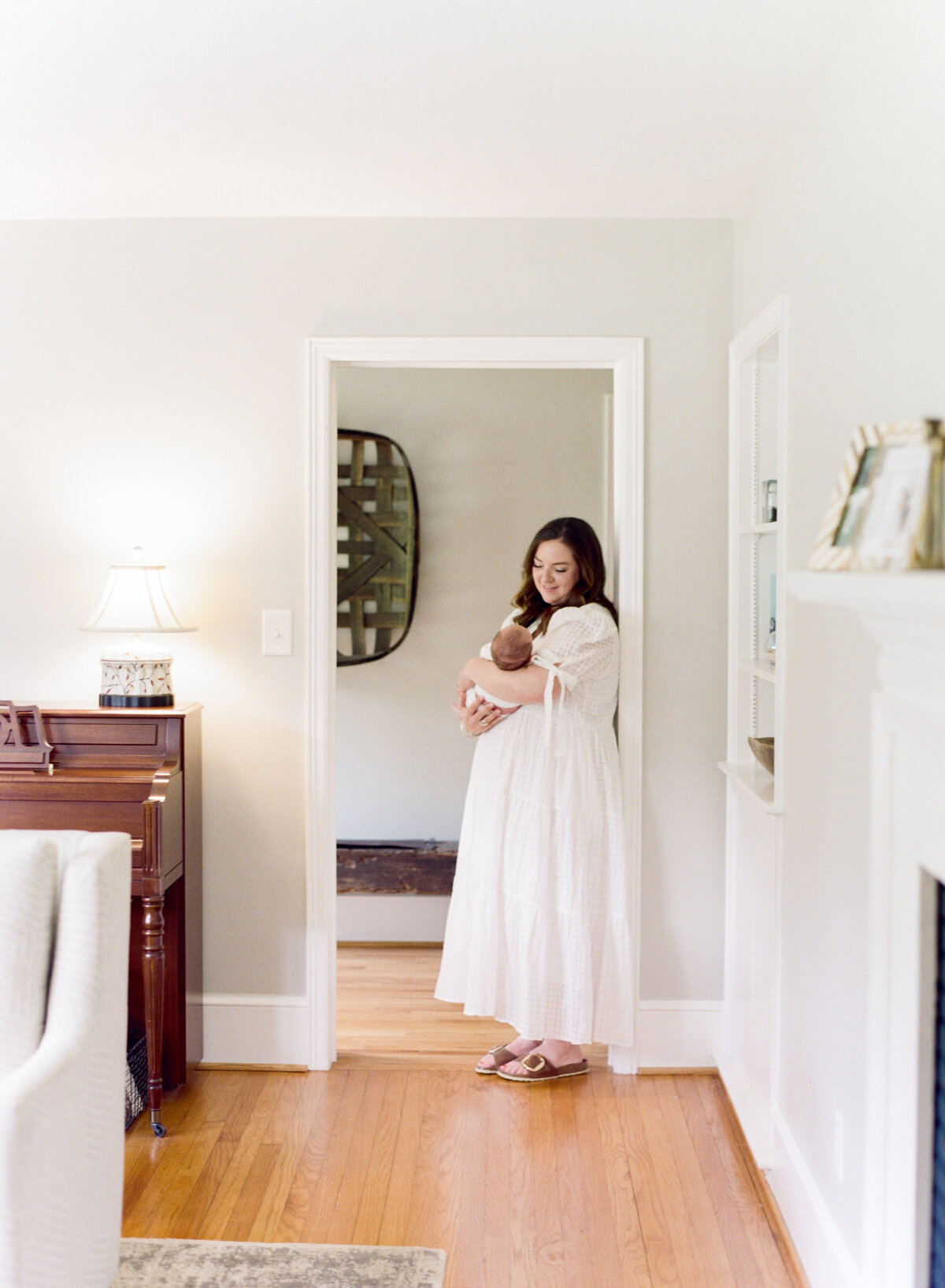 Mom leans in a doorframe and holds her baby during a lifestyle newborn session in Mebane NC. Image by Raleigh newborn photographer A.J. Dunlap Photography.