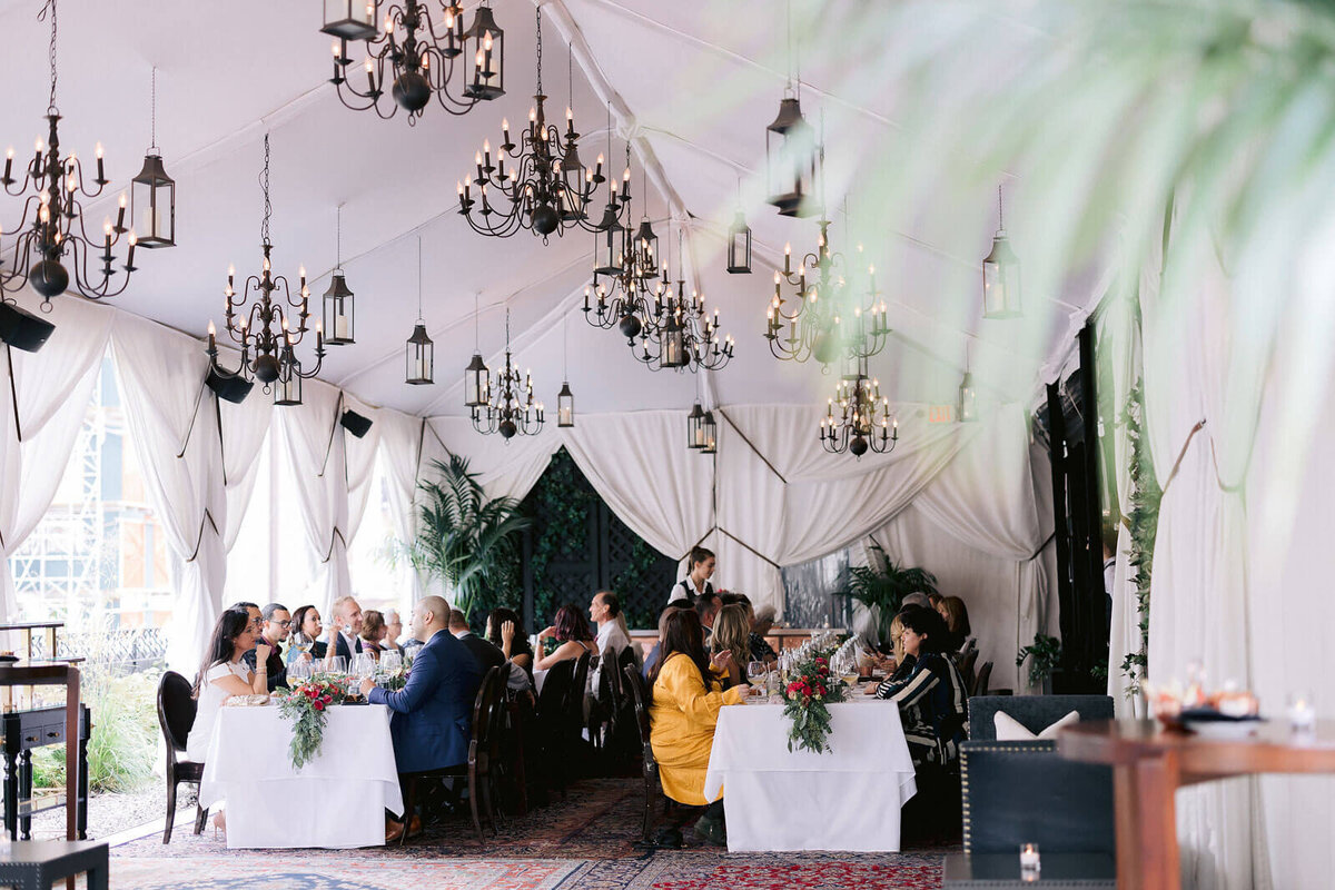 The bride and groom, together with the guests, are eating at two long dining tables in New York City. Image by Jenny Fu Studio