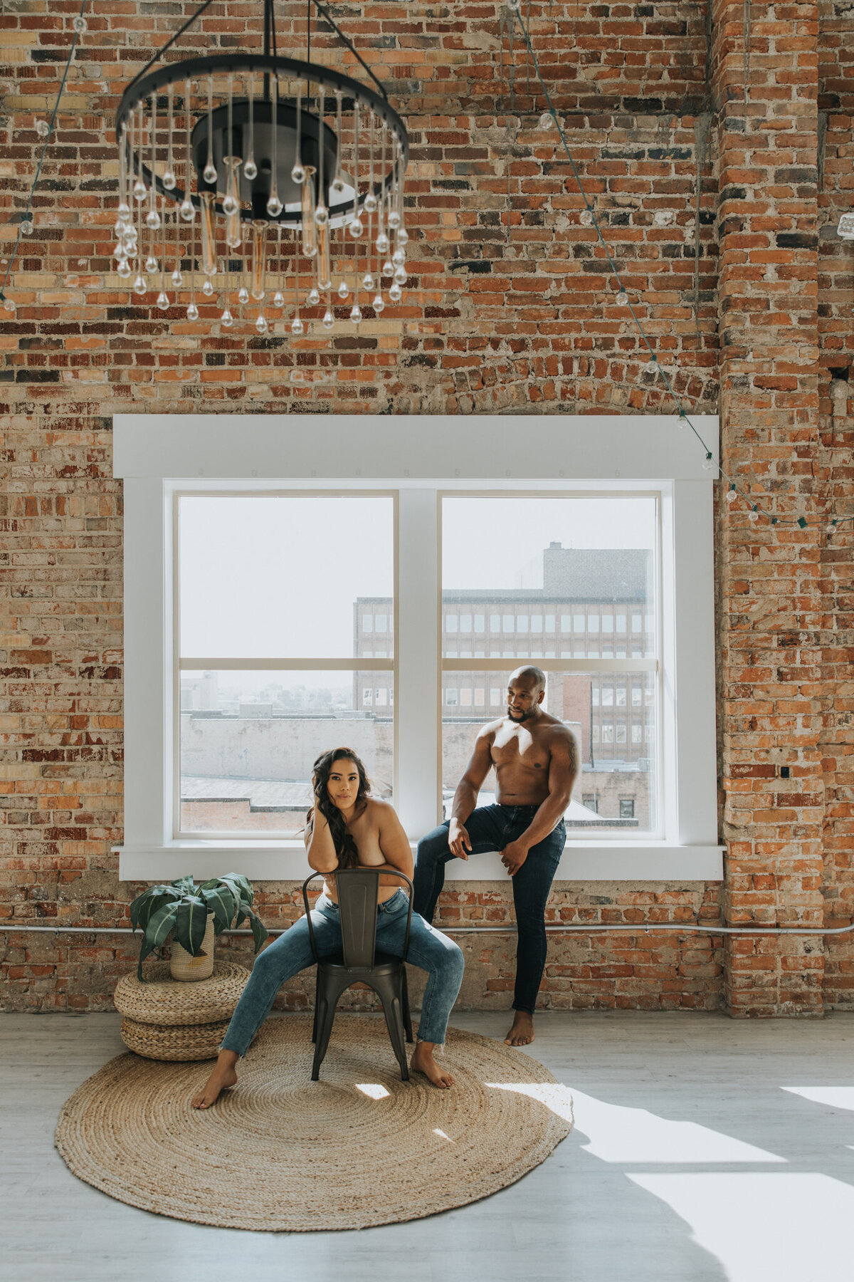 This couple is posed looking at the camera. They are both topless and are wearing jeans.