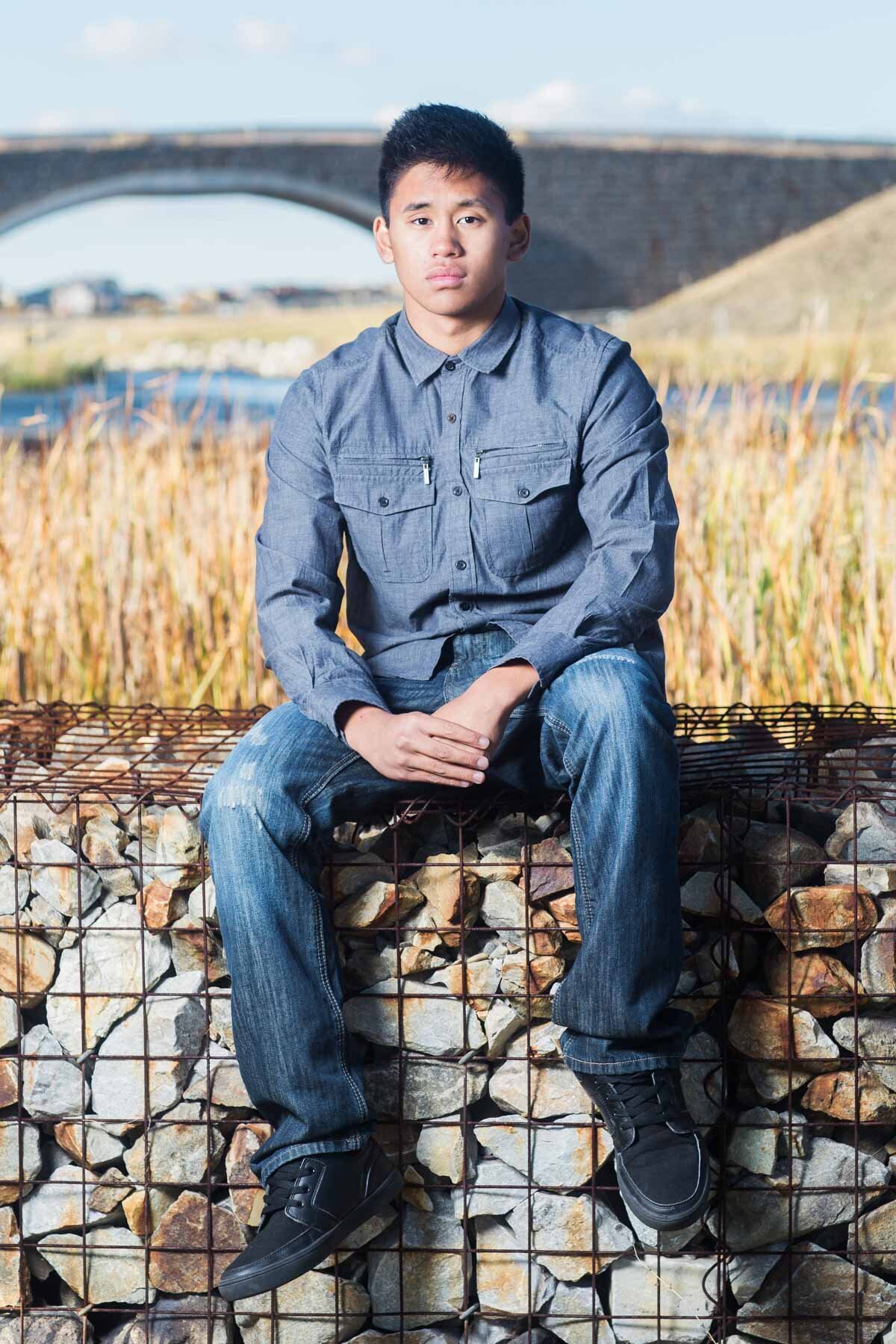 Boy posing for senior pictures on rock wall for photo session in Utah with Sara Vaz.