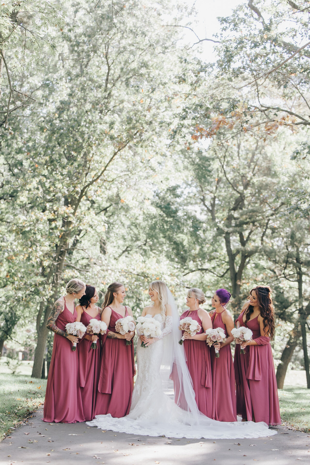 Bridesmaids wearing pink surround glamorous bride in lace
