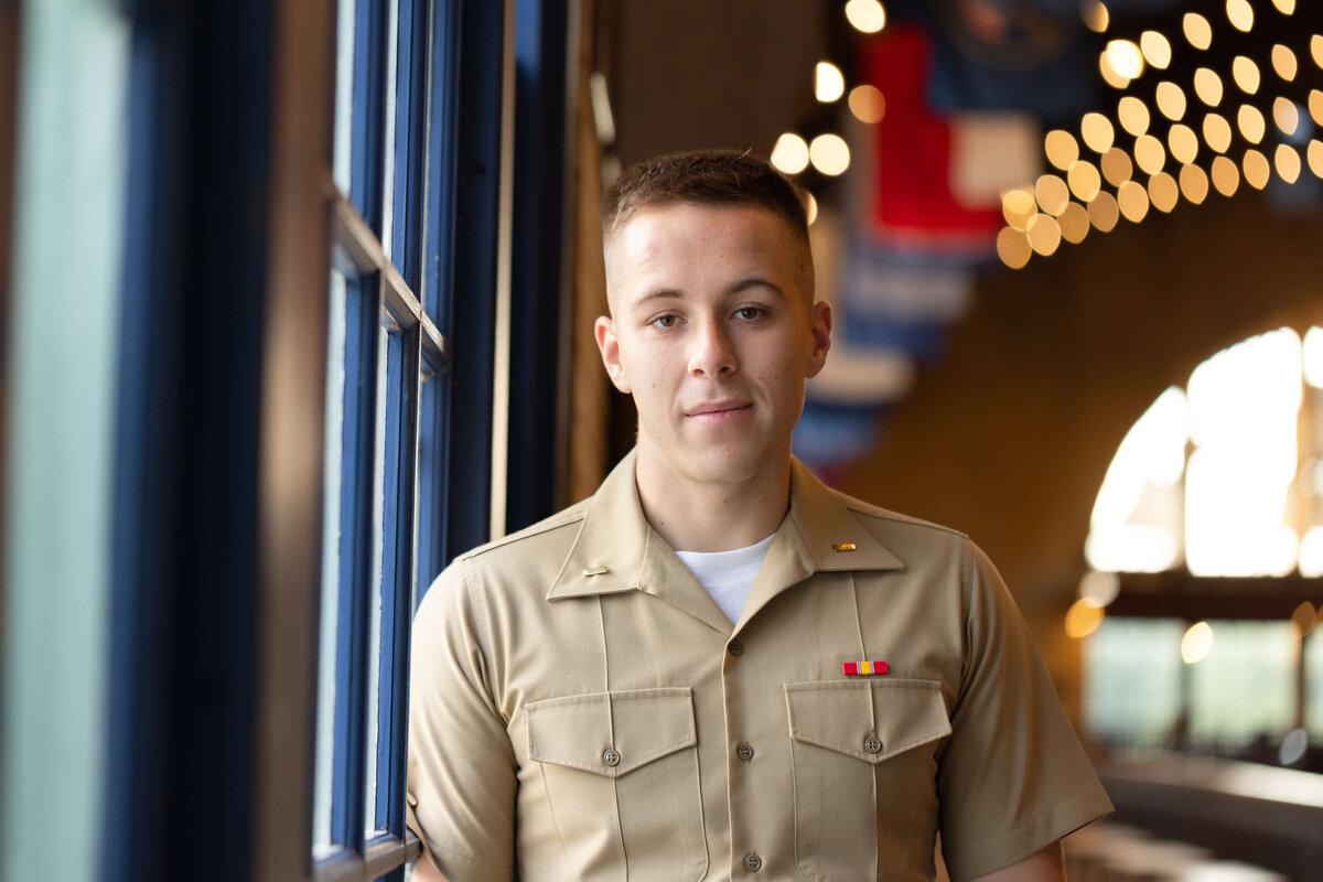 Naval Academy graduate looks out windows of Dahlgren Hall.