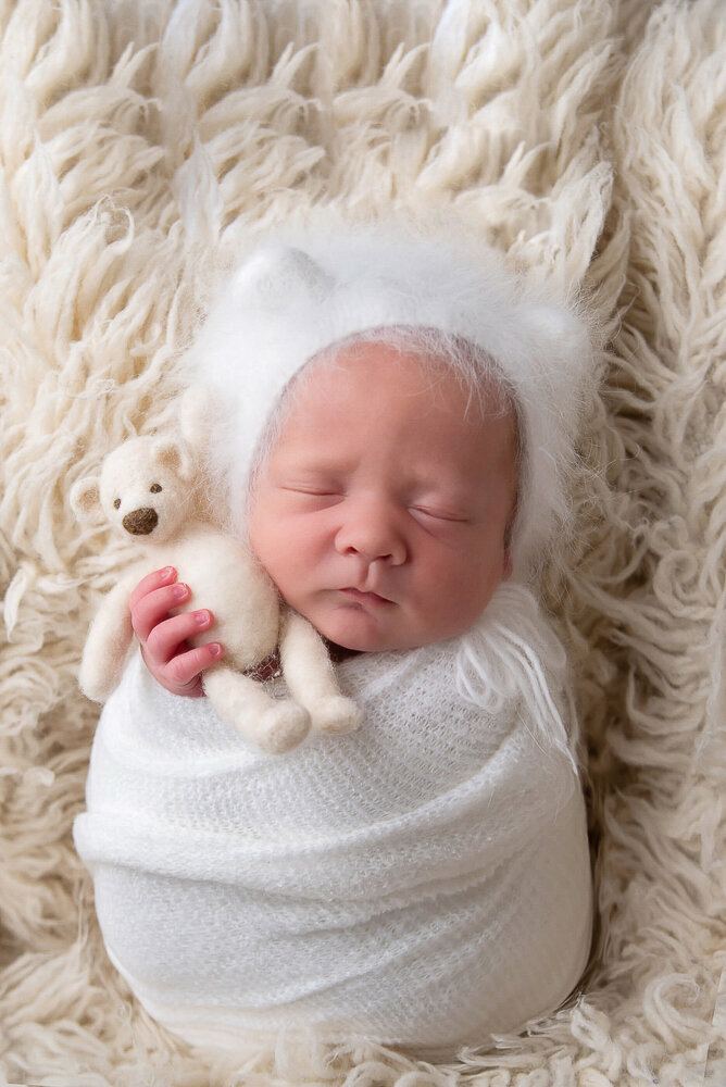 newborn baby boy wrapped in white with a white bear hat on for his Hamilton, newborn photography session.