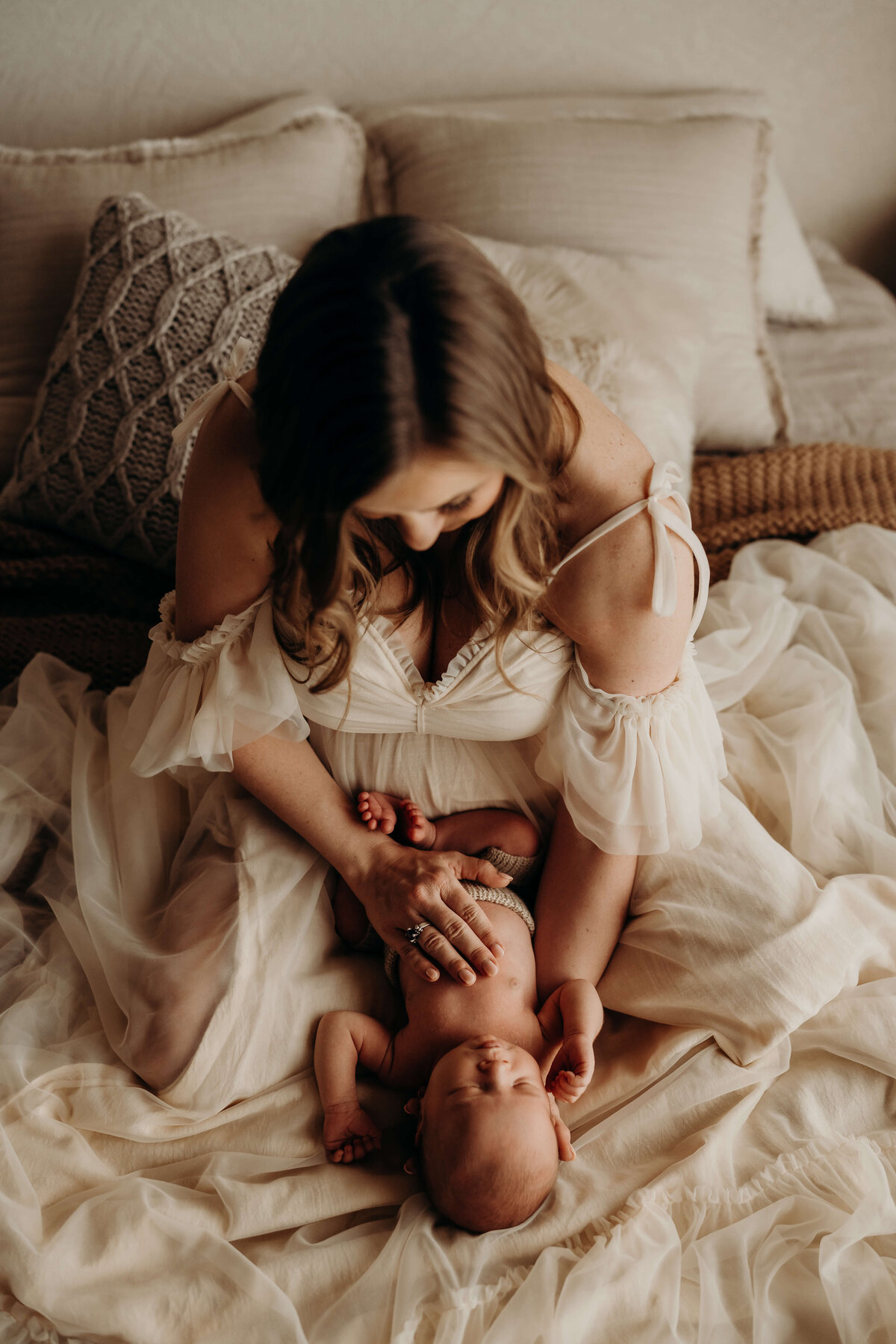 fine art portrait of mom holding newborn while wearing a chiffon dress
