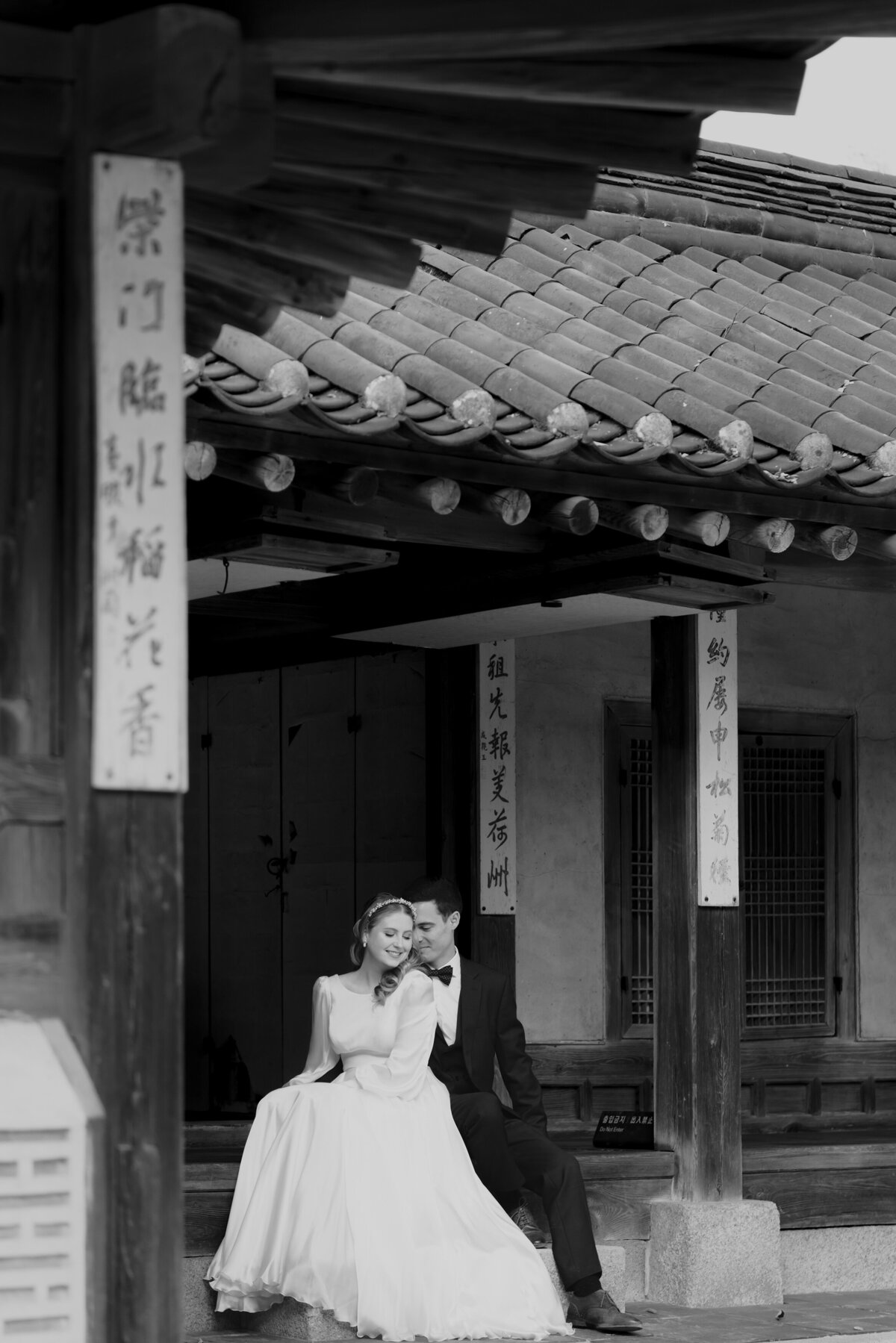 the couple sitting outside wearing their  wedding dress and suit