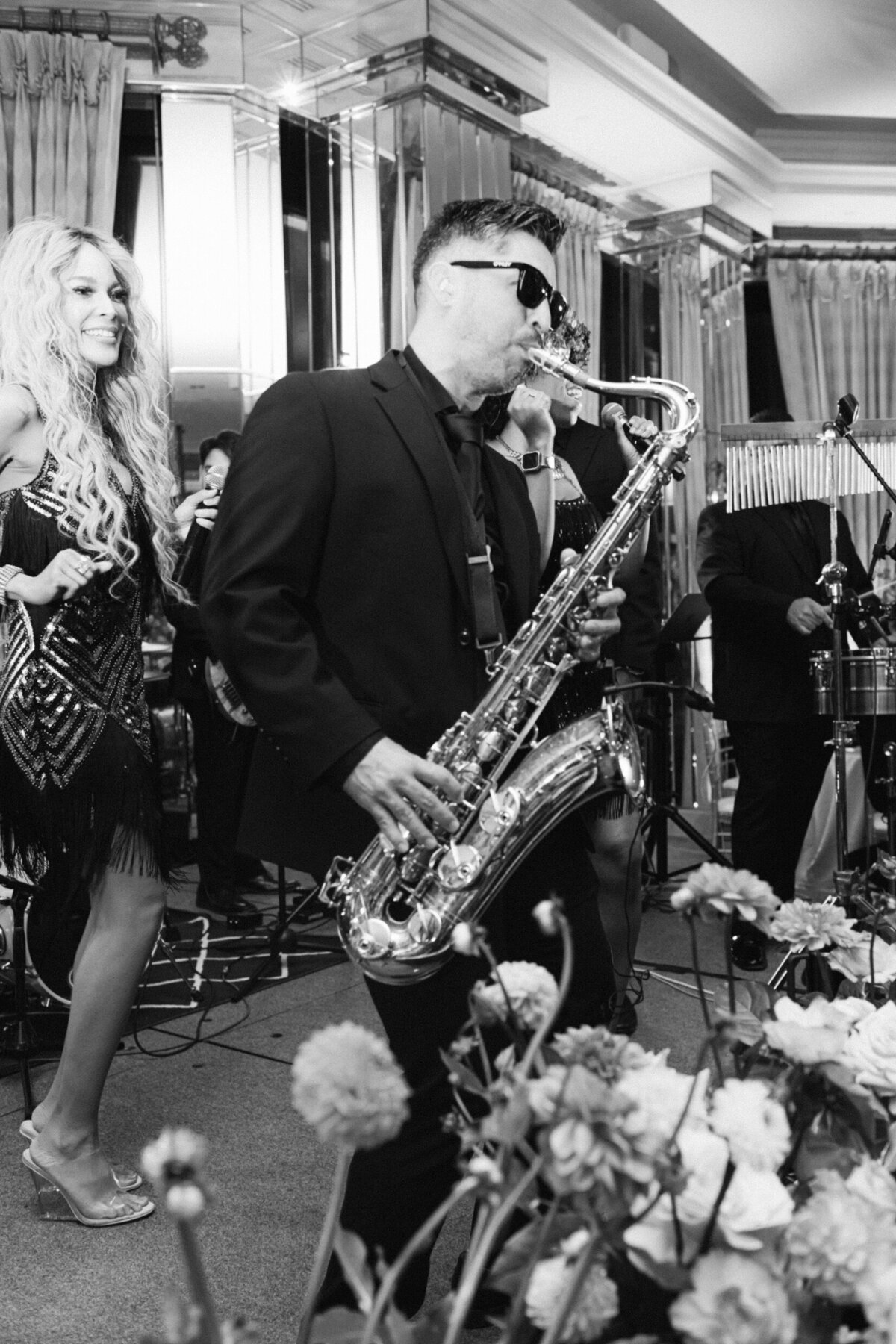 A black and white wedding photo of the saxophone player playing during the wedding reception