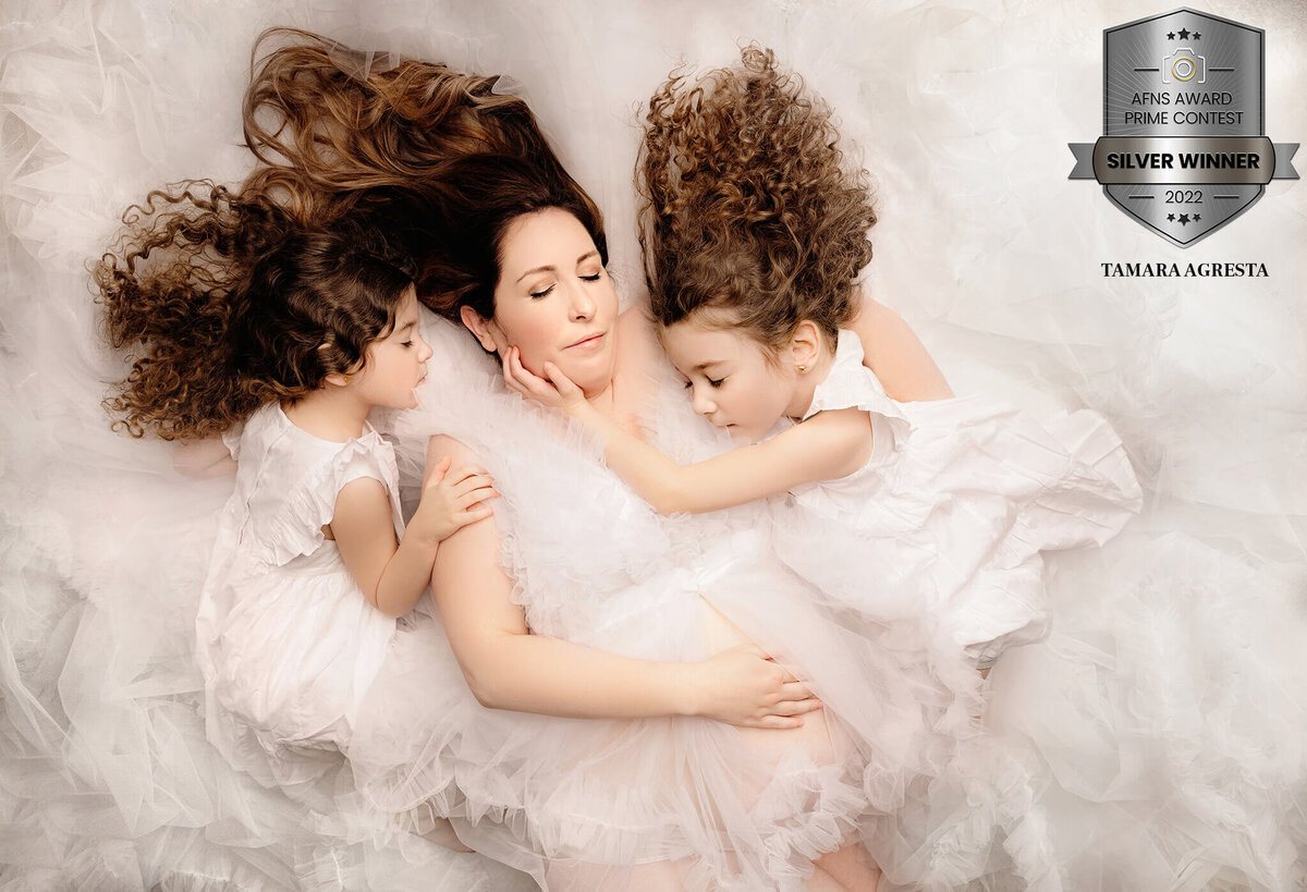 AFNS Award winning image captured by Greater Toronto Maternity Photography, Tamara Danielle portraying fine art of mom and daughters hugging pregnant belly, wearing all white.