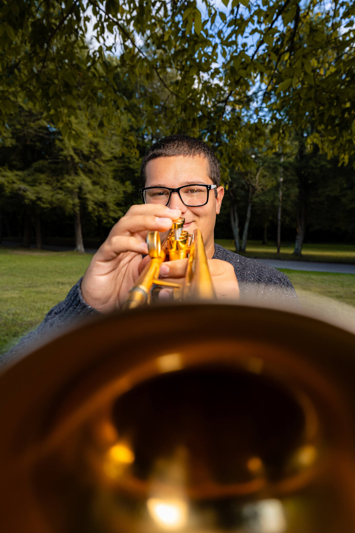 Senior portrait of a student playing his trumpet, taken on a wide angle lens with the bell of the trumpet in the foreground