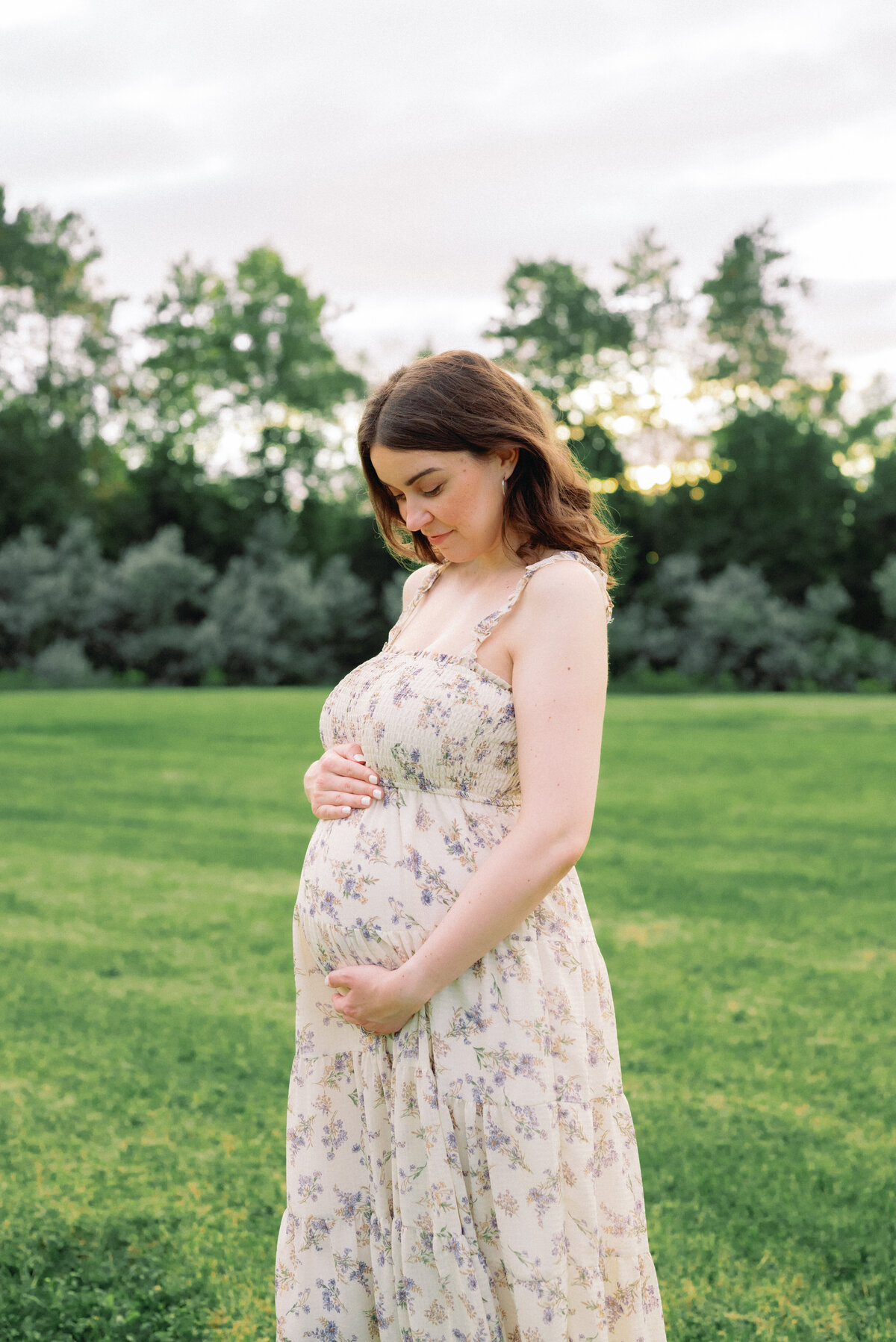 Expecting mother holding baby bump in floral dress