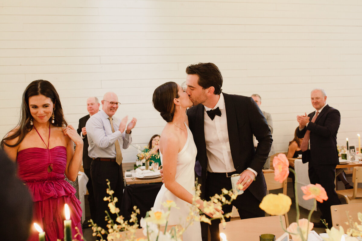 Bride and groom kissing at Wedding reception with yellow florals at Prospect House wedding Austin