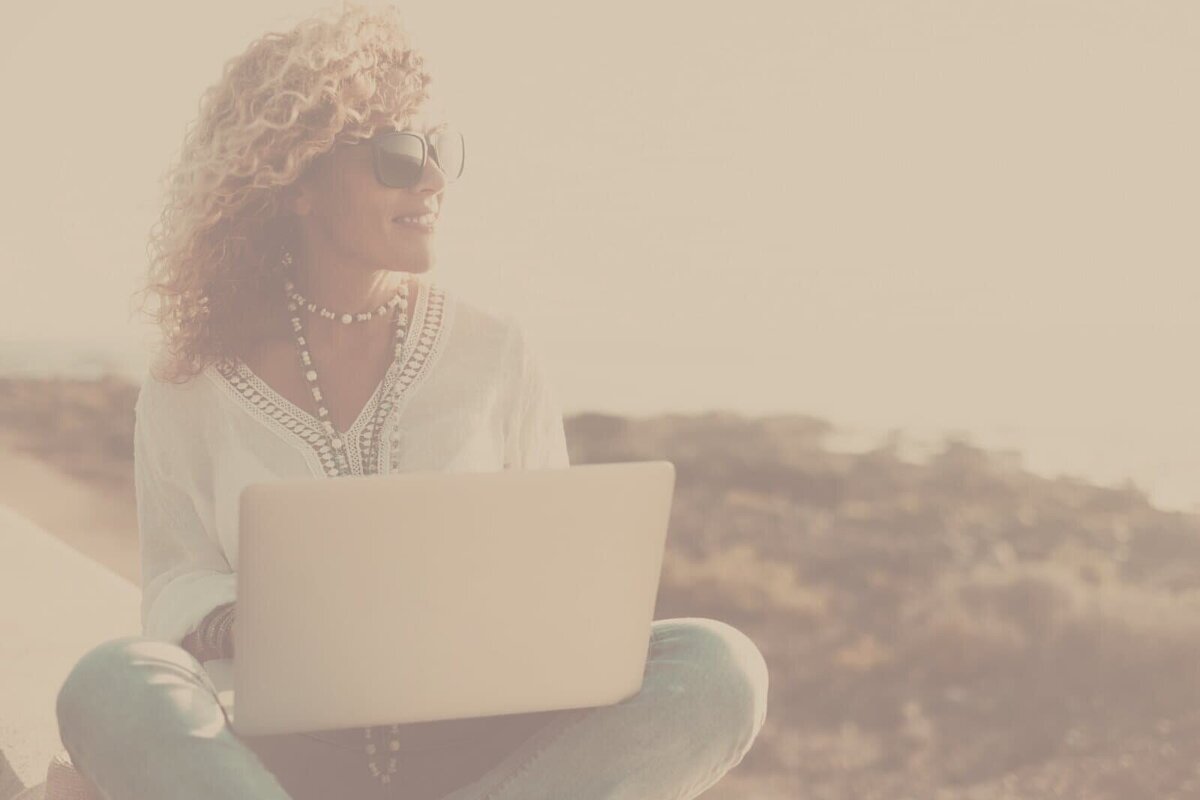 Woman working outside on laptop, representing creative entrepreneur building a website and online course