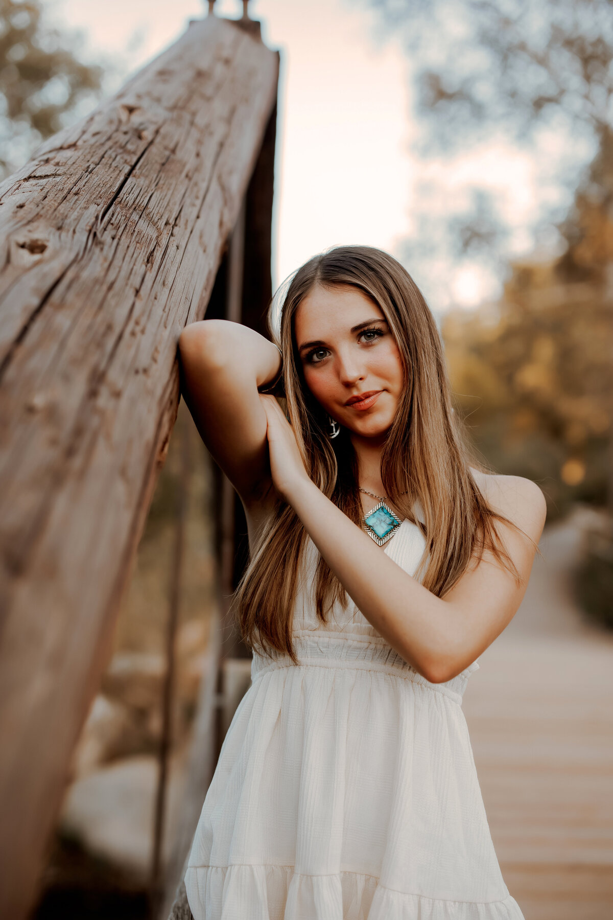 Girl leaning against her arm on a large wooden bridge for senior photos in Boulder, Colorado