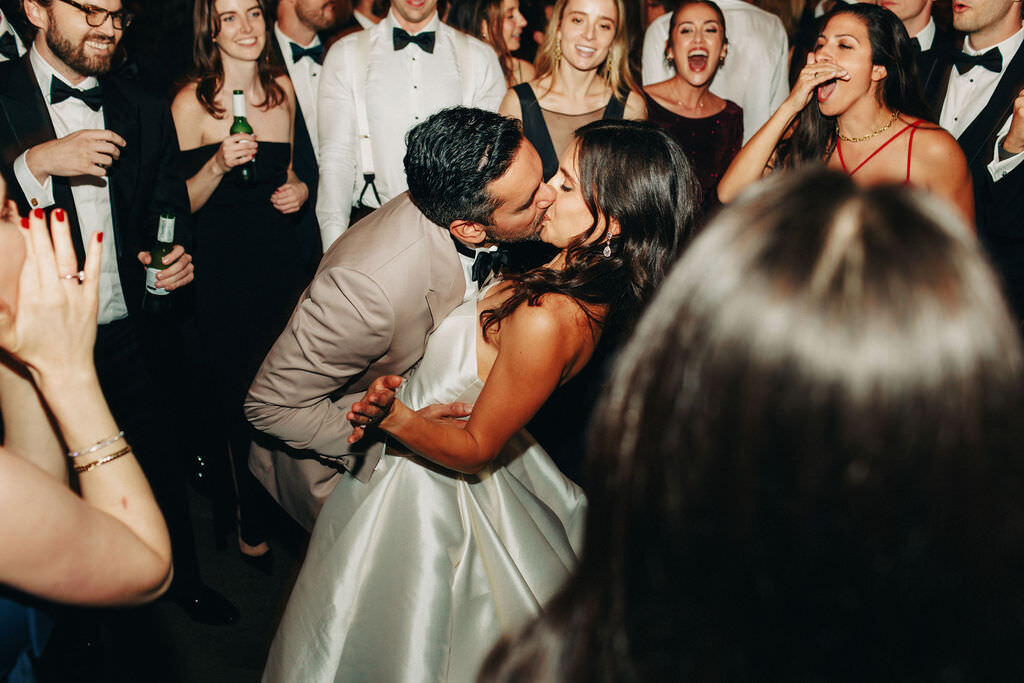 first-dance-brideandgroom-share-kiss-surrounded-by-guests
