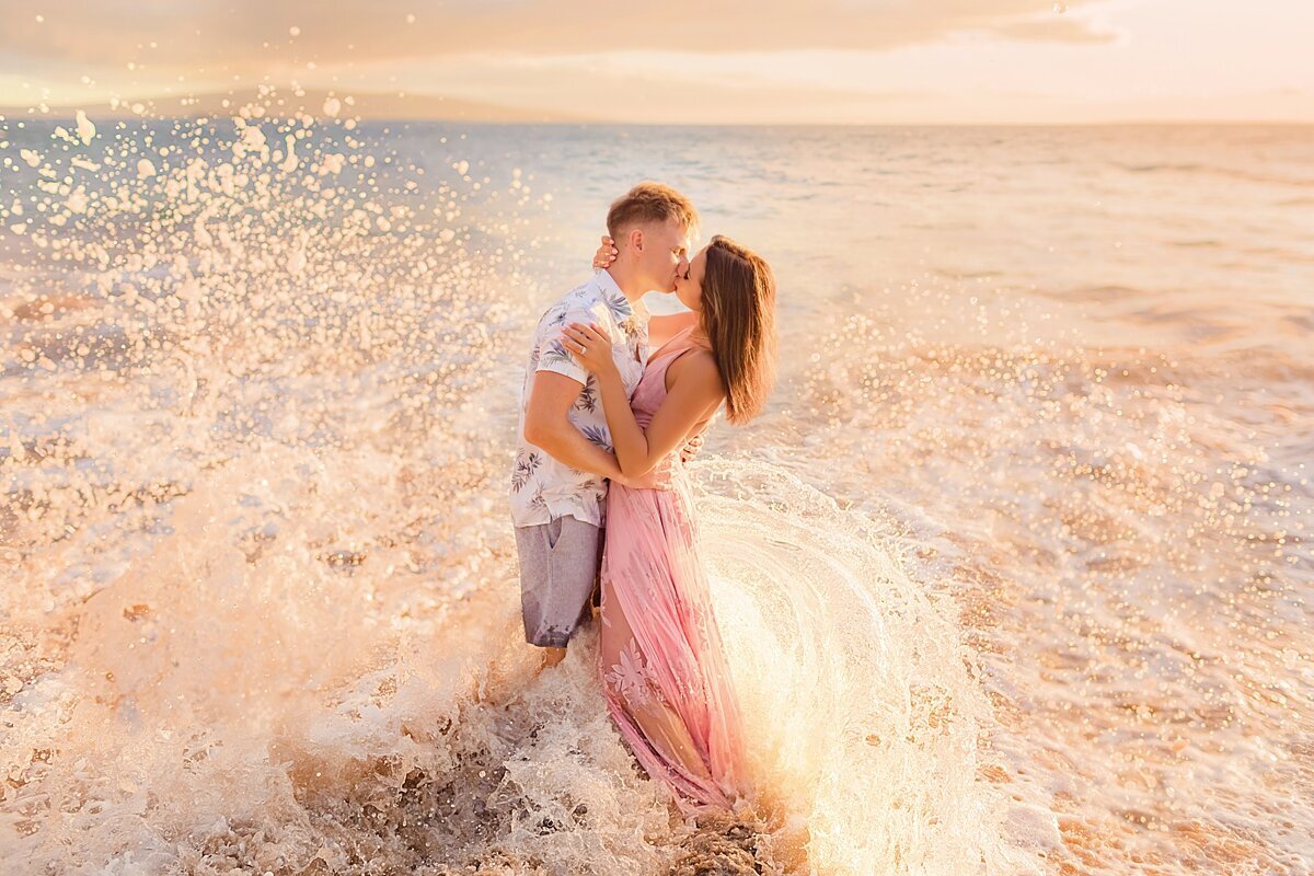 Wave splashes a couple at sunset for their proposal portraits in Wailea