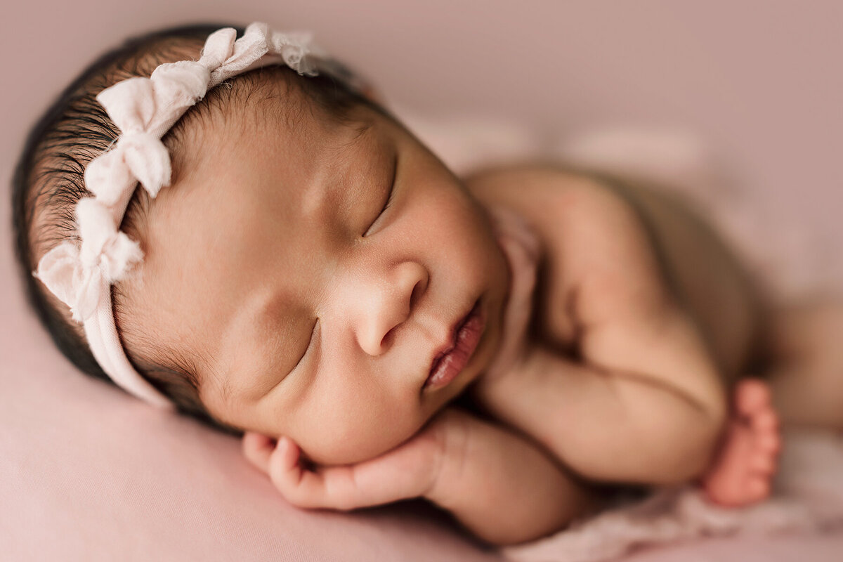 Fort Collins Newborn photos of baby laying on a blanket with her hands on her fave