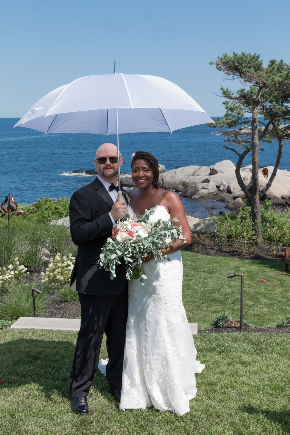Bride holding her floral bouquet while groom holds a clear umbrella