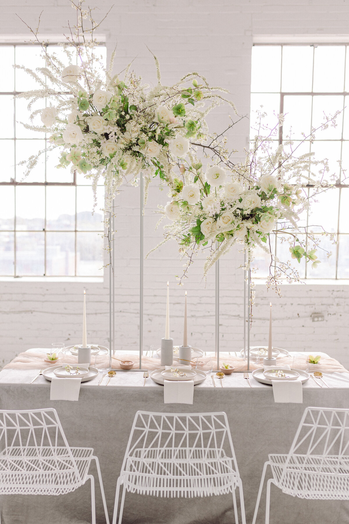Airy centrepieces of white flowers and greenery are elevated above a table for a wedding at L’Eloi.