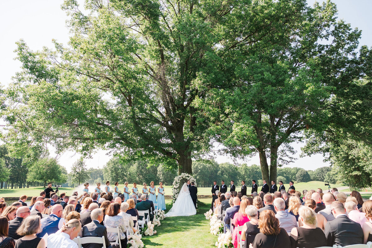 wedding ceremony under a large tree on the golf course at The Grand Resort during a summer sunny day