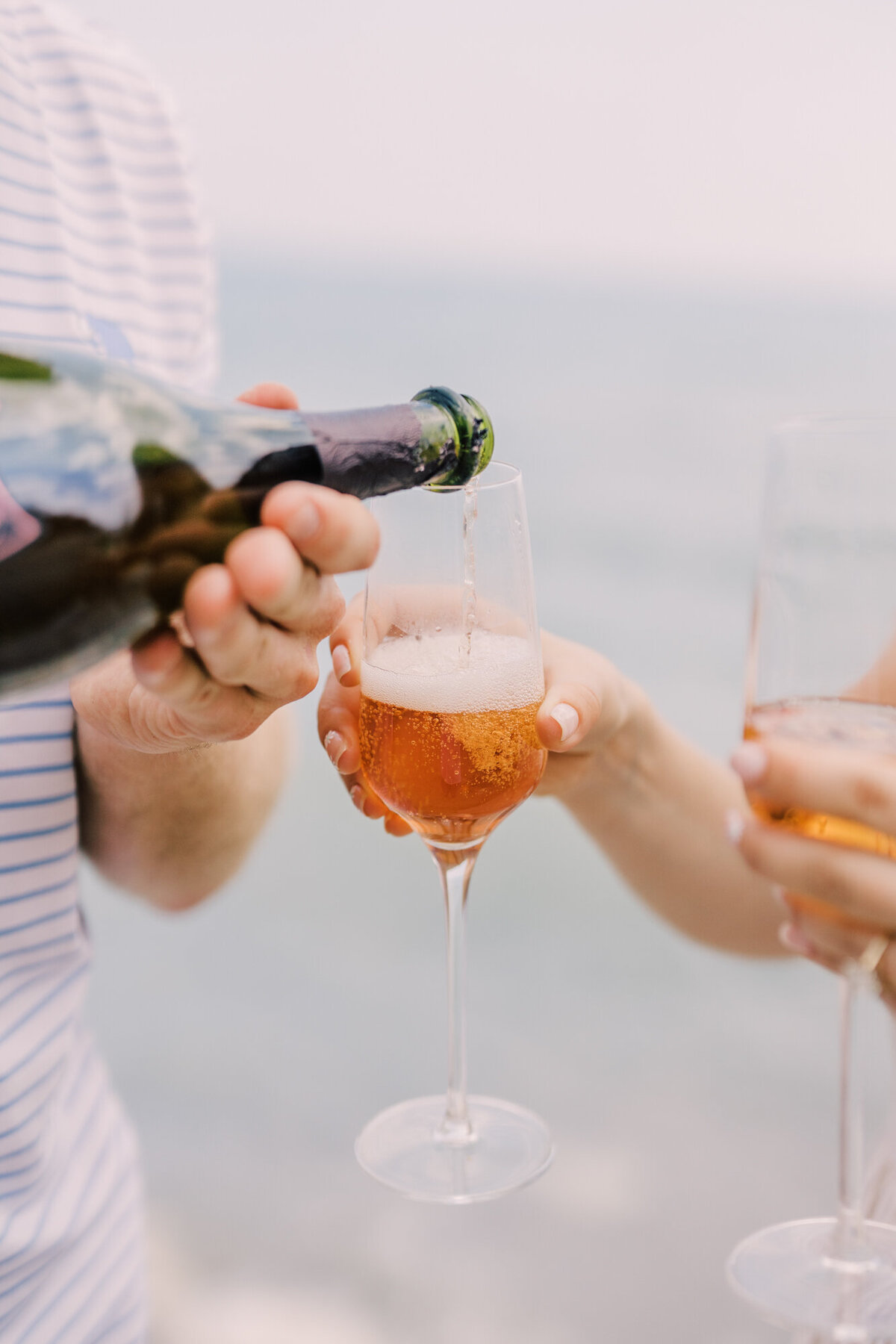 A couple pop open a bottle of Dom Perignon in front of beautiful Lake Michigan