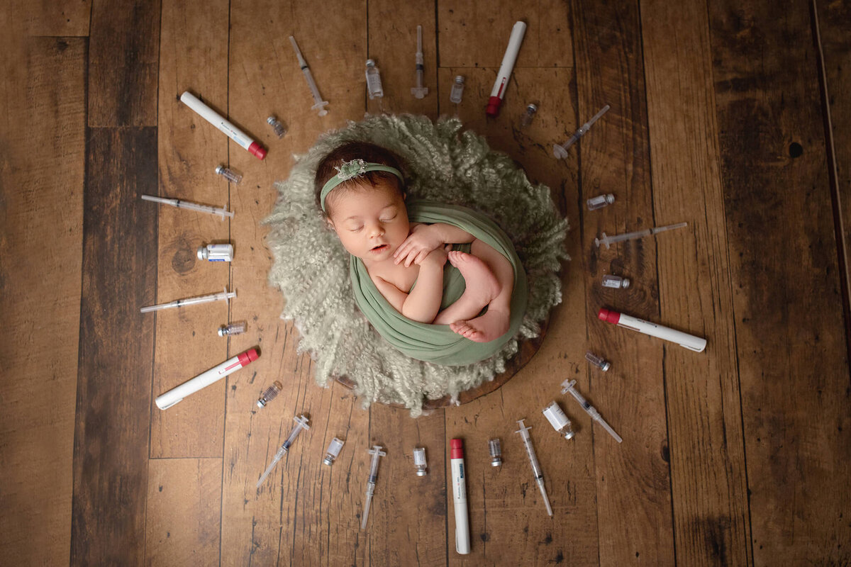 portrait of newborn baby surrounded by ivf needles at hamilton photography studio