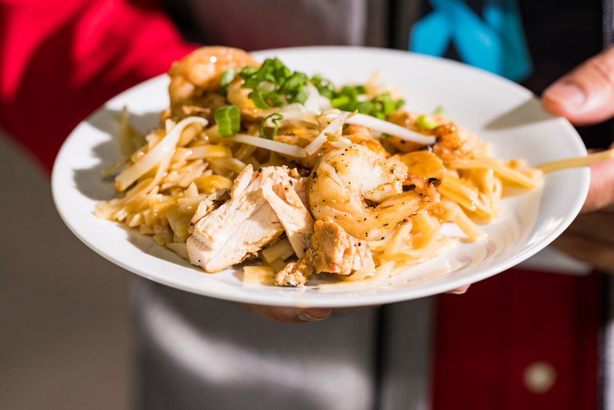 Plate of pasta with chicken and shrimp topped with scallions