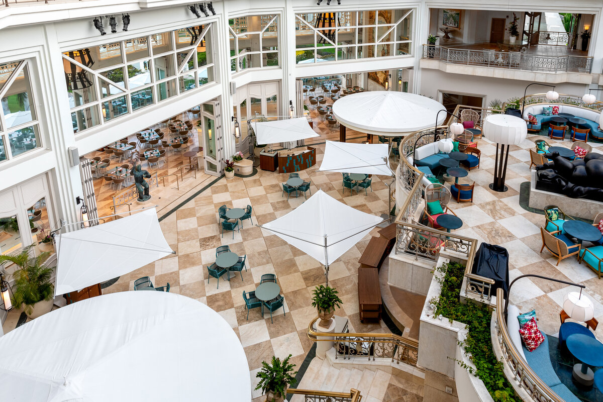 An overhead view of the main atrium at the Grand Wailea, Maui, showing the additional seating area with umbrella tables and the detached bar.