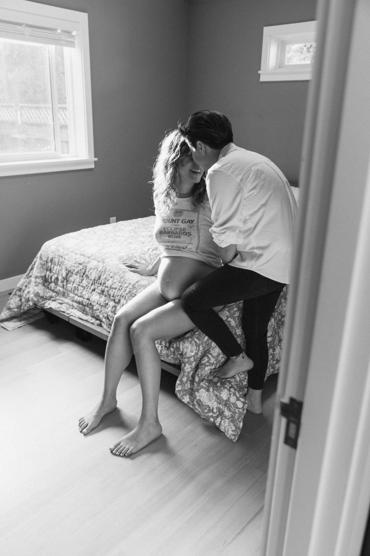 Black and white image of two mothers kissing during a maternity photoshoot.