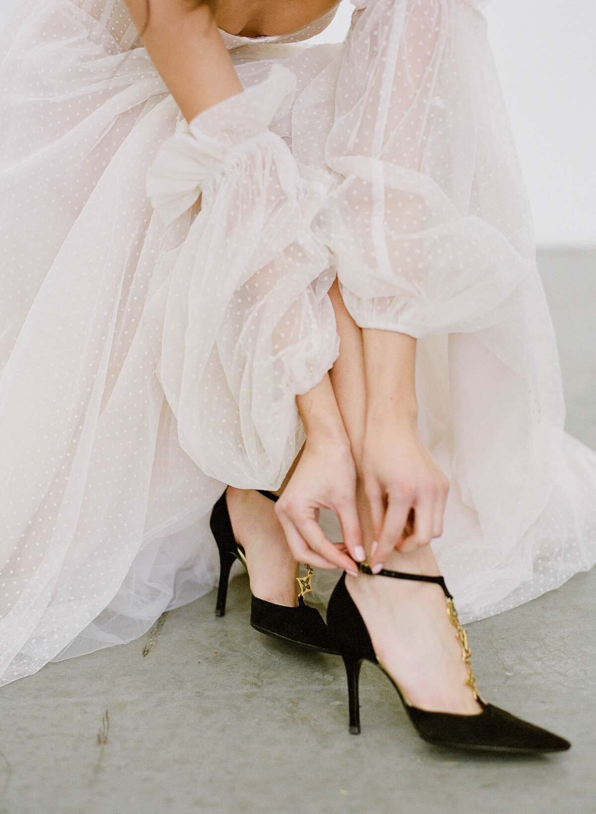 bride putting on black louis vuitton wedding shoes