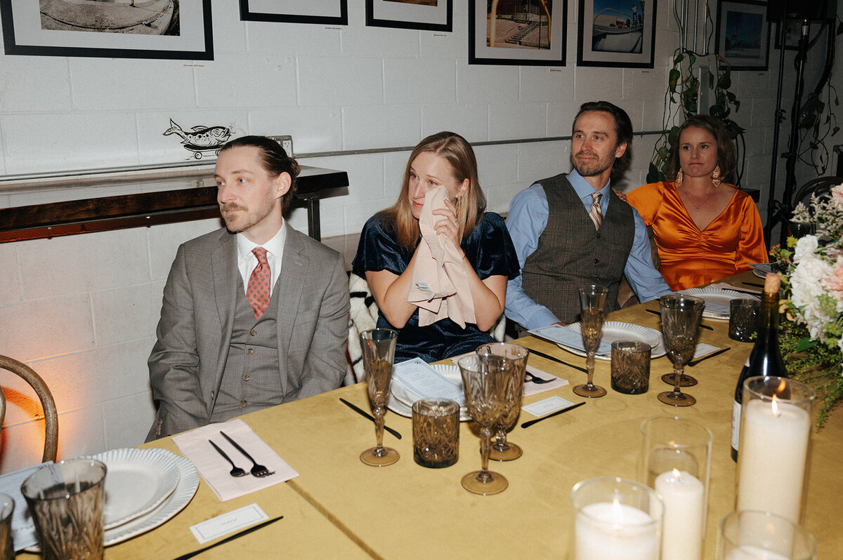 A group of people seated at a table during an indoor vow renewal.