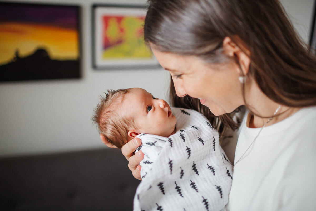 Mom smiling at newborn daughter during at home Toronto Newborn photography session