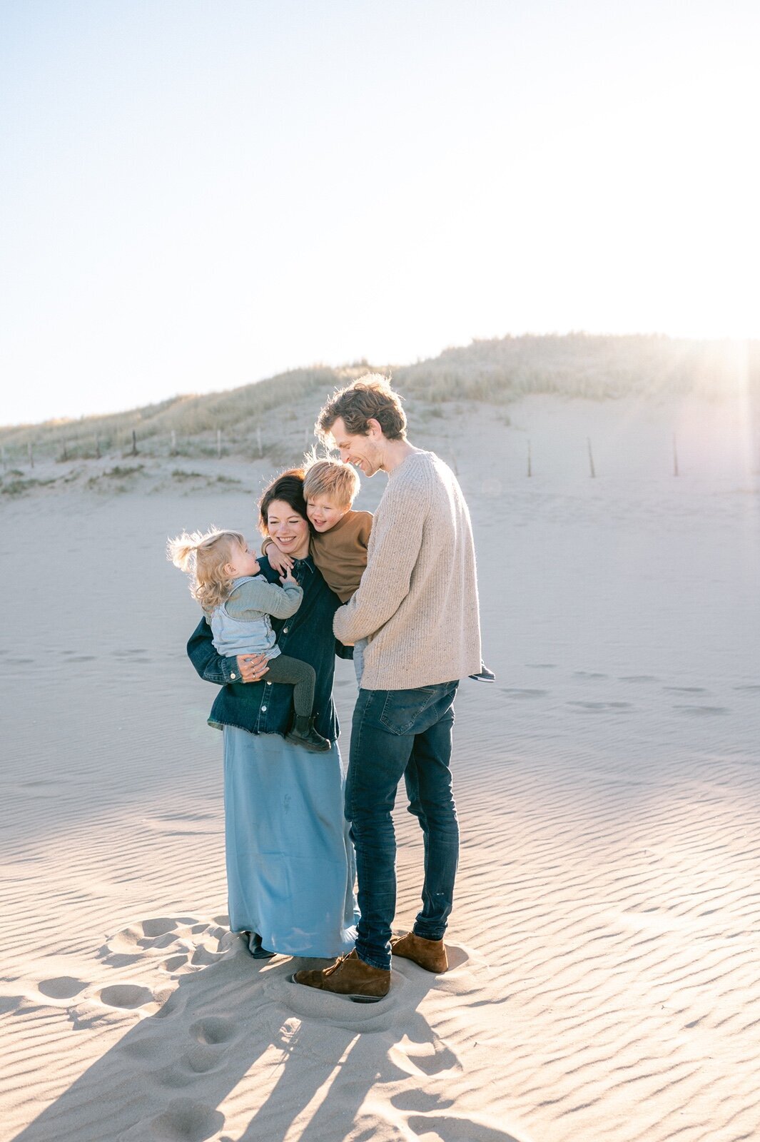 Gezin staat met elkaar te knuffelen op het strand