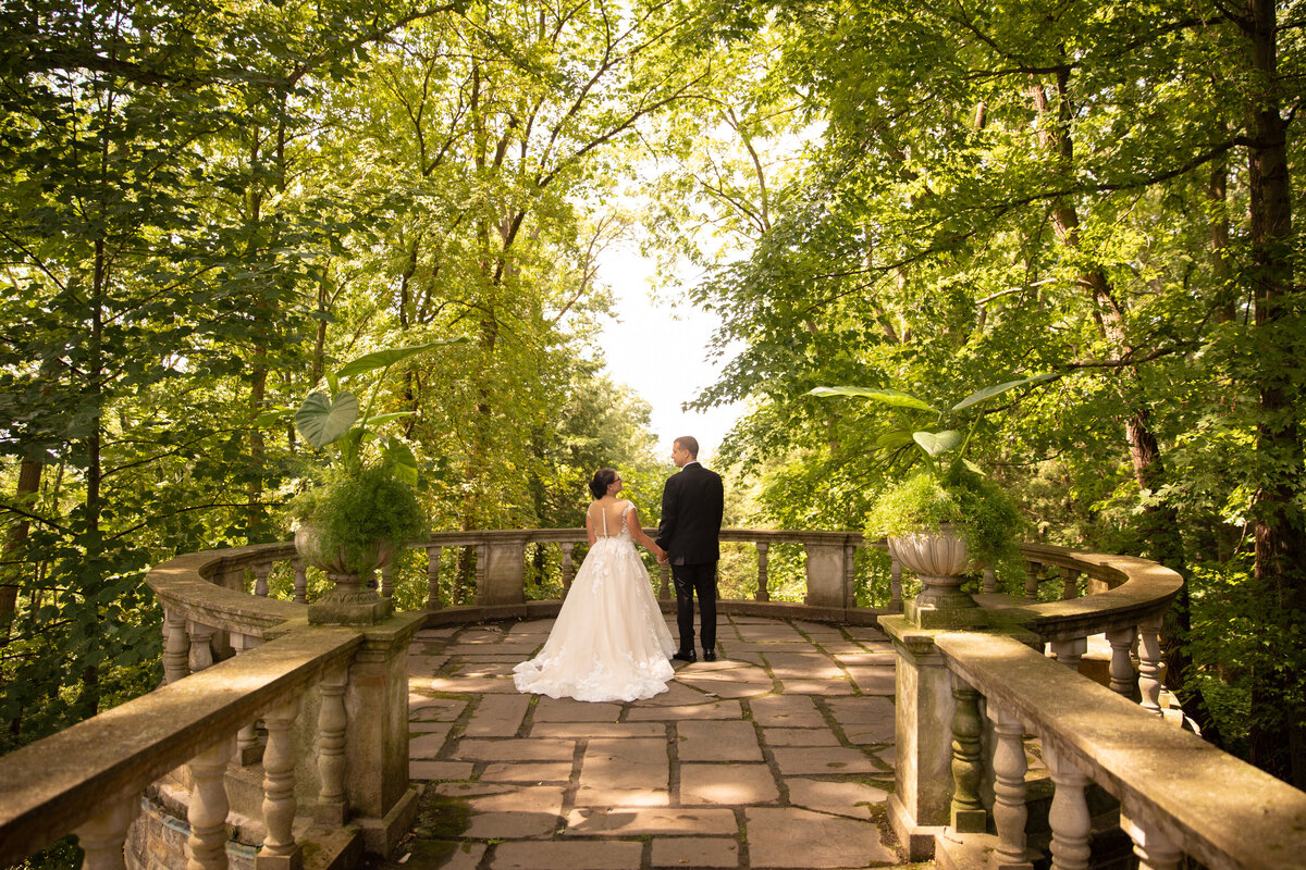 Bride and groom hold hands while looking at each other and taking in the moment alone on their wedding day at the Overlook of Stan Hywet Hall & Gardens. Photo taken by Aaron Aldhizer