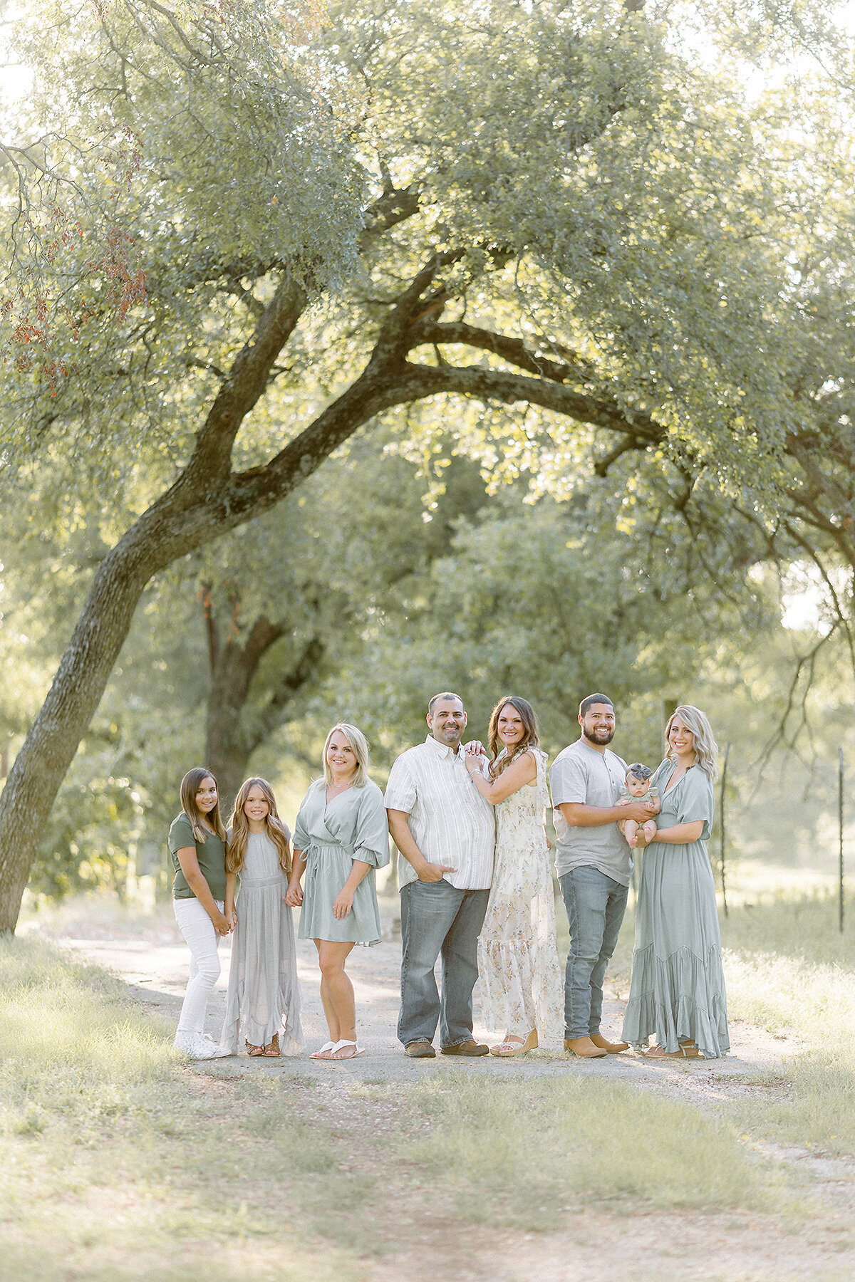 A Dallas family photo taken while they are posing close together in the middle of a path at a local Dallas/Fort Worth park for their family portrait session.