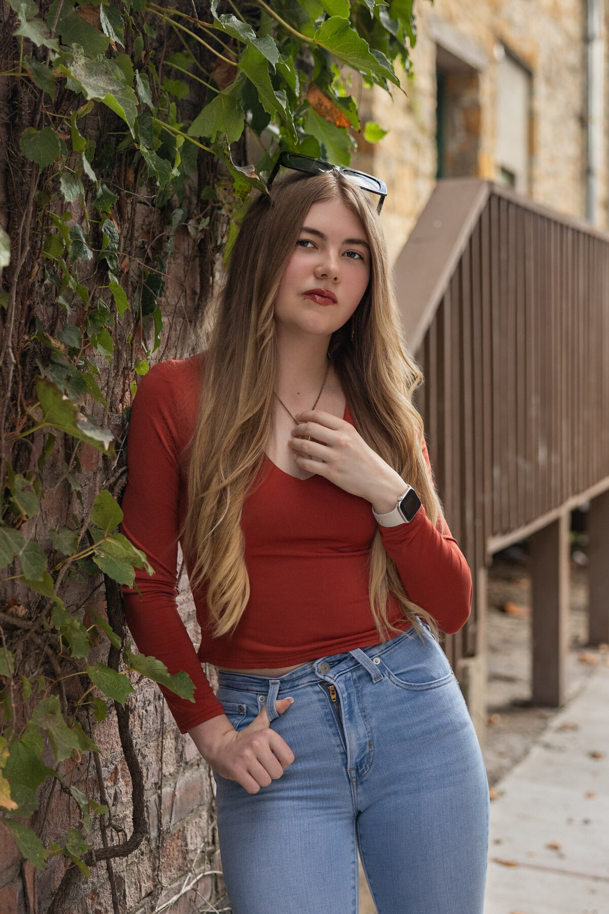 A senior girl leaning against a wall in ivy in downtown Lawrence, KS