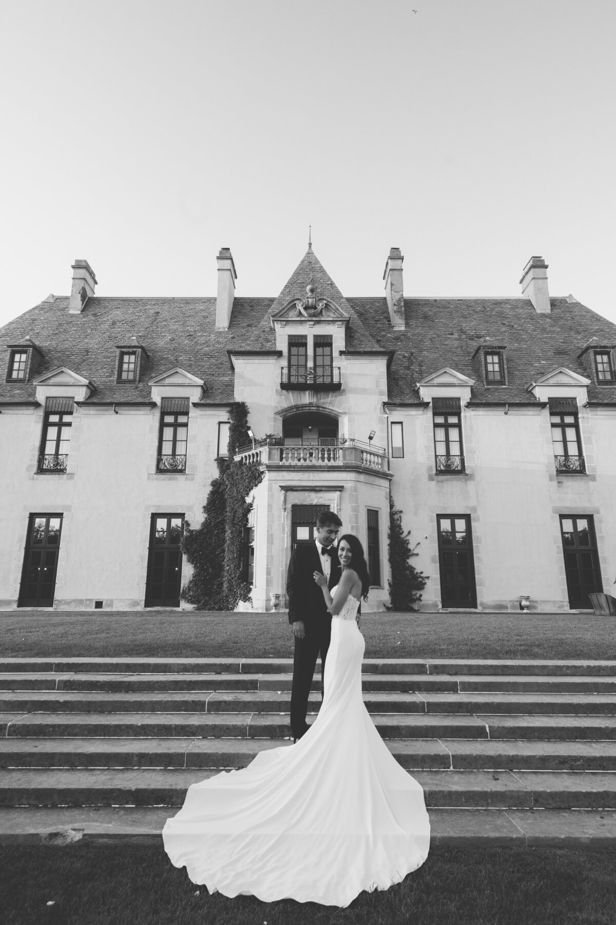 bride and groom standing in front of Oheka Castle